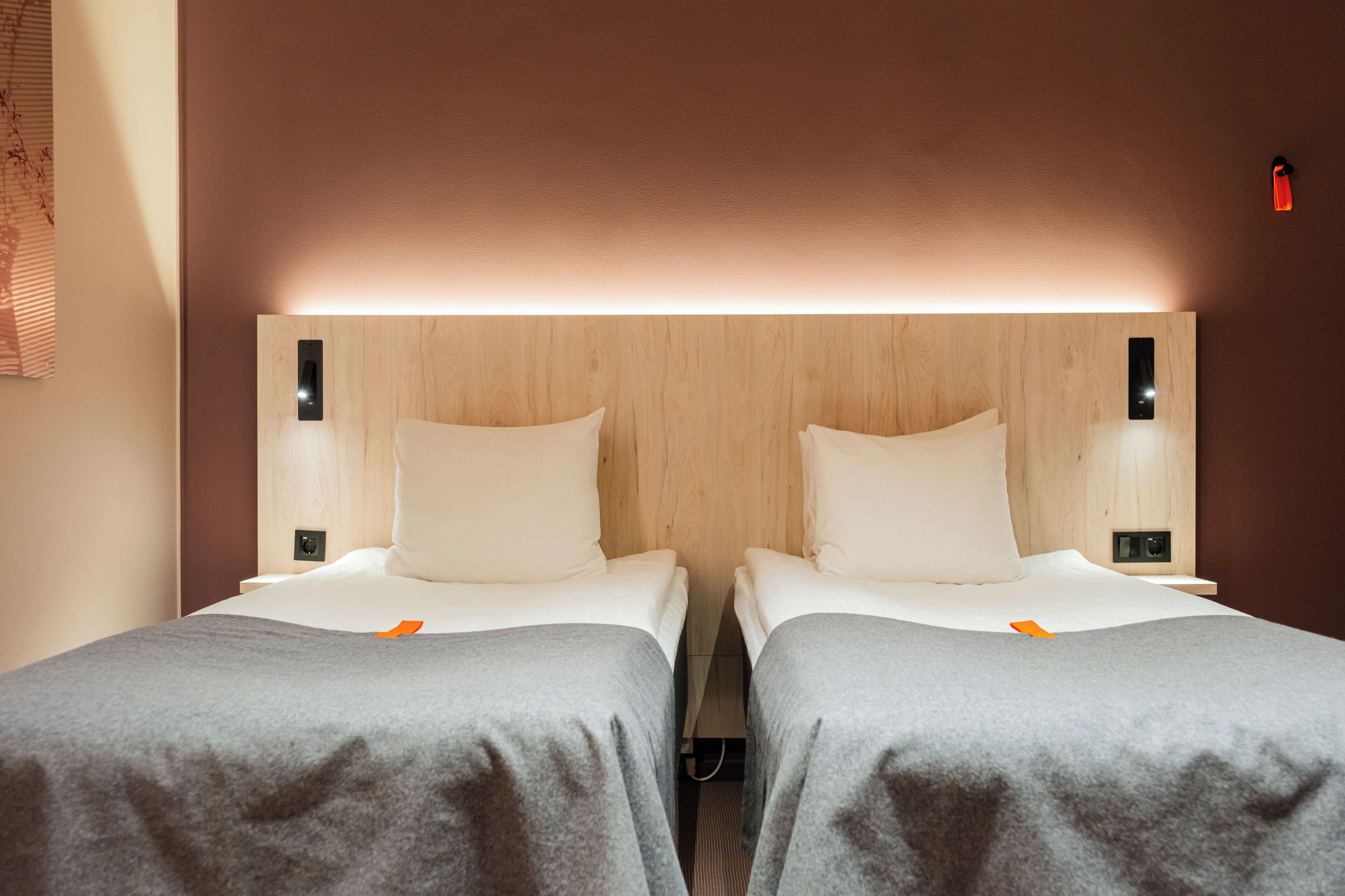 A hotel room with two single beds, wooden headboards, and bedside lamps.