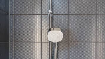 Doccia con soffione a mano e soffione fisso a parete, decorata con piastrelle a texture.