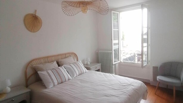 Een slaapkamer met een bed, nachtkastjes, een stoel, een radiator en een raam.