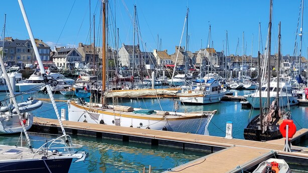 A marina with numerous boats docked, wooden walkways, and buildings in the background. - 2-room garage facing with panoramic view of the sea and TATIHOU island (UNESCO) (Saint-Vaast-la-Hougue)