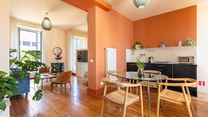 Un vaste espace de vie comprenant une table ronde en verre, des chaises en bois et un canapé.