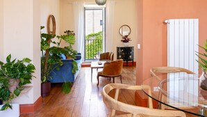 Un vaste espace de vie doté d’un plancher en bois, d’un canapé bleu, d’une table en verre et de plusieurs chaises.