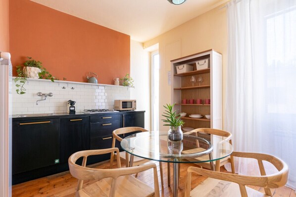 Una cocina moderna con gabinetes negros, una mesa de vidrio y sillas de madera.