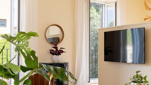Un salon avec une grande télévision, un piano et une plante en pot.