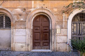 Un edificio histórico con una gran puerta de madera ornamentada y dos ventanas arqueadas con rejas de metal.