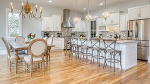 A spacious kitchen with white cabinets, a large island with bar stools, and modern stainless steel appliances. - Sleeps 18 | Luxe 30A Beach Home w/ Resort Pool + Outdoor Fireplace (Santa Rosa Beach)