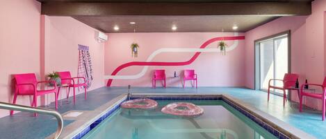 A swimming pool area with pink chairs and a red and white wall design.