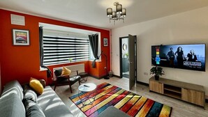 A modern living room with a sofa, a coffee table, a TV, and a colorful rug. - Sandringham House Contractors, Families, Holidays (Cleethorpes)