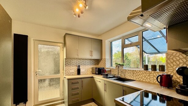 A modern kitchen with a large window, built-in cabinets, and a countertop. - Sandringham House Contractors, Families, Holidays (Cleethorpes)