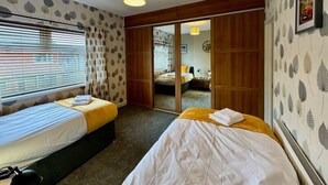 A hotel room with two beds, a large mirror, and a view through a sliding door.