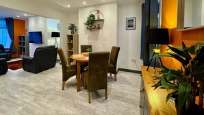 Un salon moderne comprenant un coin repas, un téléviseur et une bibliothèque.