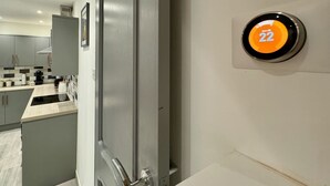 Une cuisine moderne avec des meubles gris, un plan de travail blanc et une serrure numérique affichant le numéro 22.
