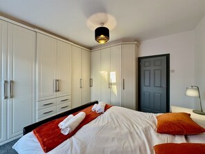 A hotel room with a bed, white wardrobe, and a door.