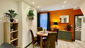 Un coin repas comprenant une table ronde, des chaises, un buffet et une plante.