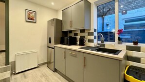 Une cuisine moderne avec des meubles gris, un four encastré, un four à micro-ondes et un évier.