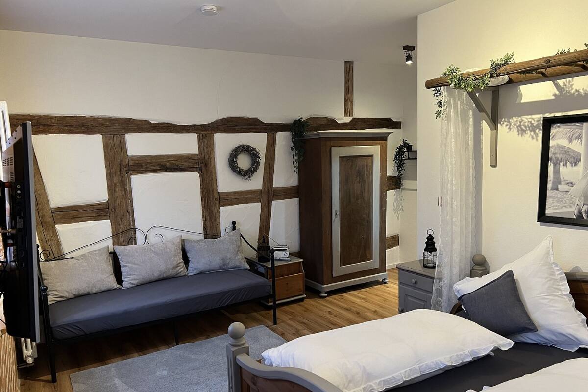 A bedroom with a bed, a sofa bed, a wardrobe, and a small table.