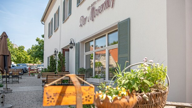 A building with a sign reading "Der Moserhof" and outdoor seating with tables and chairs. - Der Moserhof (Oberaurach)