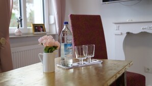 A table with a bottle of water, a vase with flowers, and two glasses. - Der Moserhof (Oberaurach)