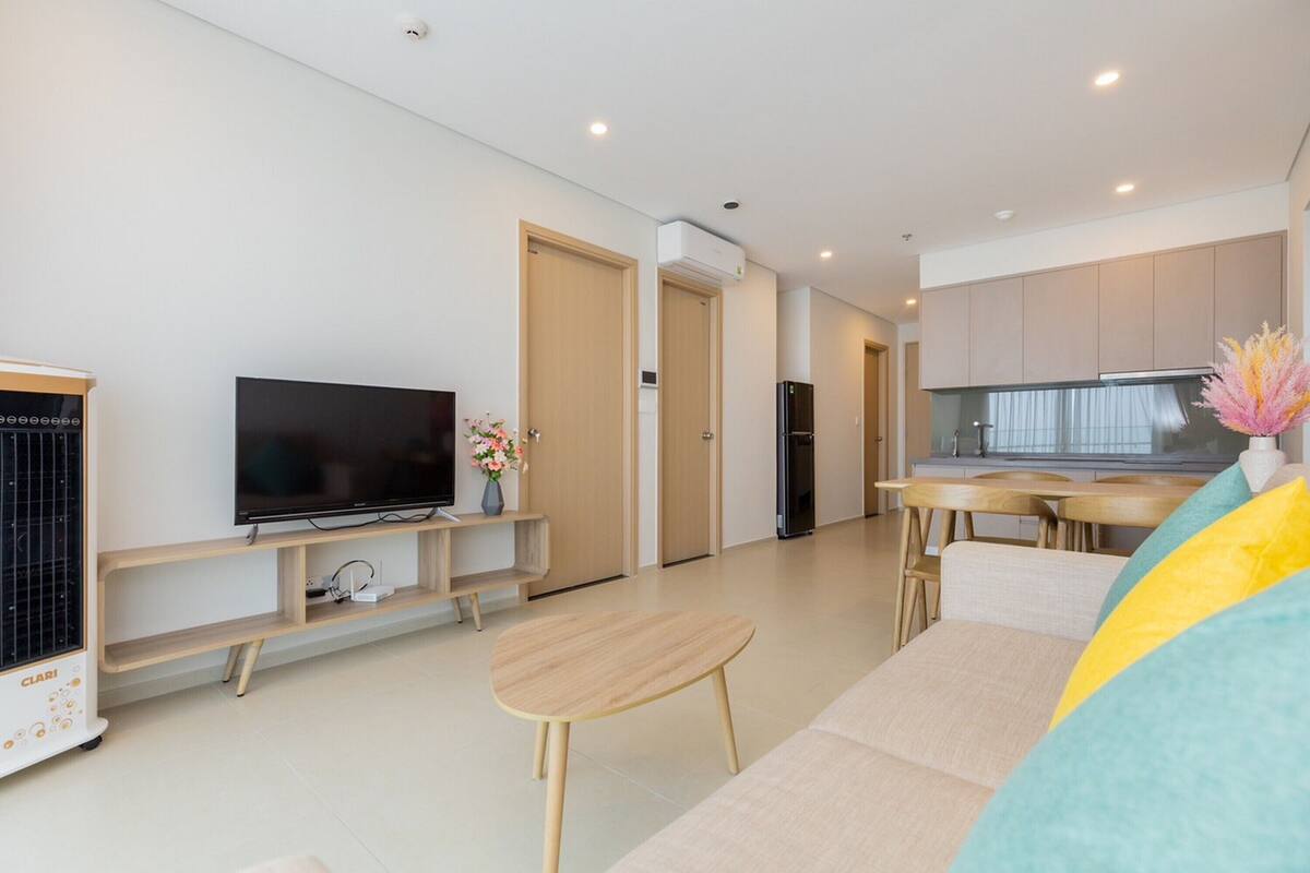 Una sala moderna con televisor de pantalla plana, una mesa de centro de madera y un sofá.
