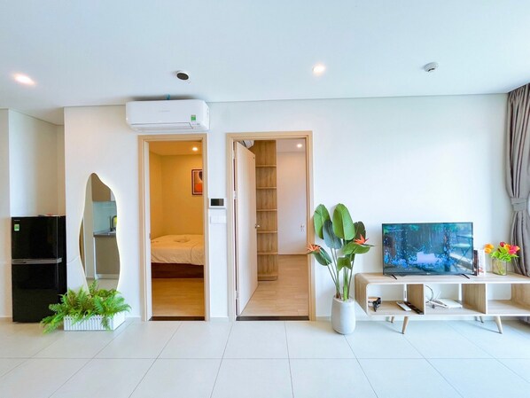 A modern living room with a TV, a plant, and a bookshelf.