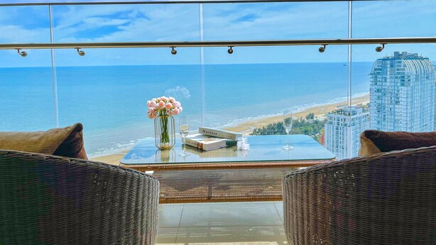 A balcony with wicker furniture, a glass table, and a vase of flowers. - The Song Sunny Canopy (Ho Chi Minh City)