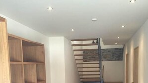 Een modern interieur met een trap, houten planken en een blauw vloerkleed.