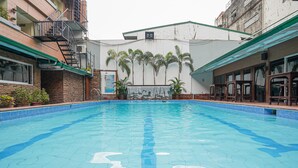 A swimming pool with a tiled deck, surrounded by buildings with balconies and potted plants. - Arzo Hotel Manila (Manila)