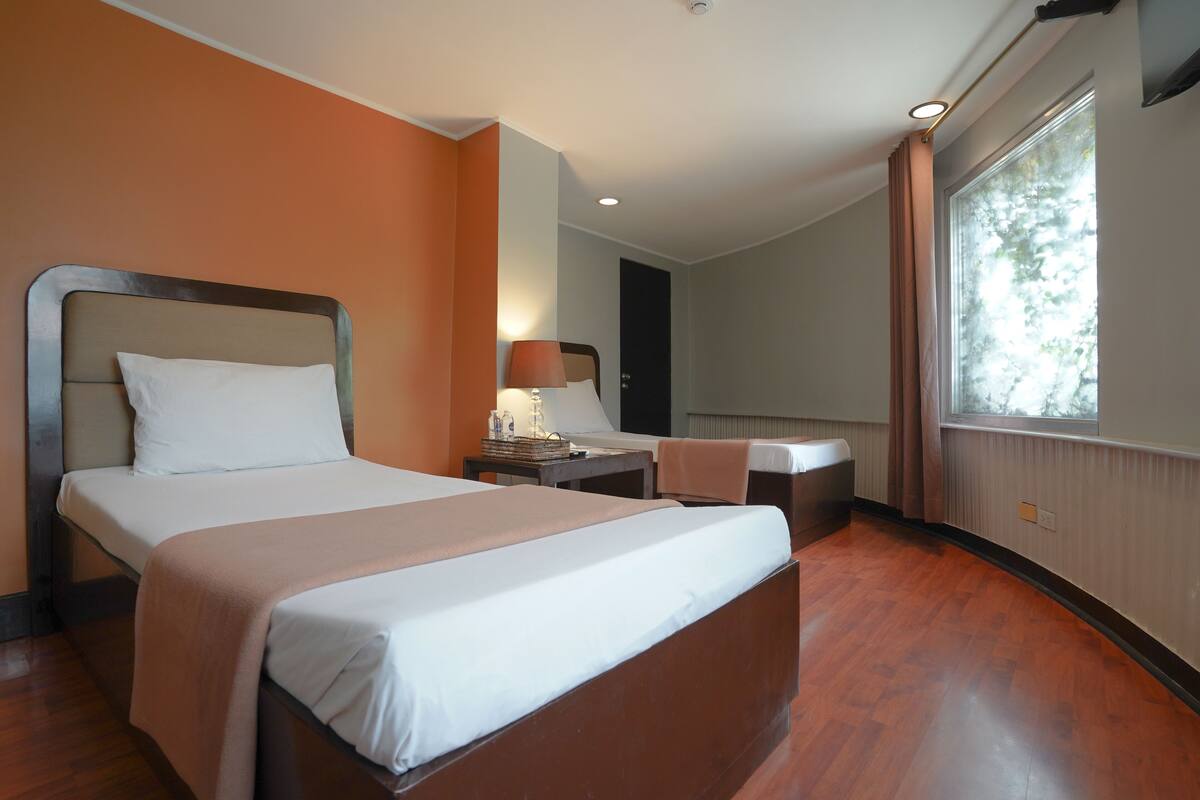 A hotel room with a large bed, a desk, and a window.