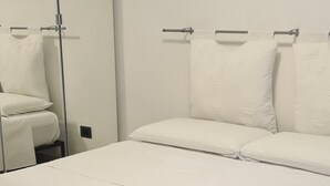 A neatly made bed with white bedding and two rolled towels with a white ribbon.