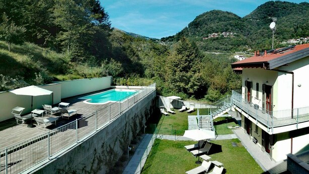 A rooftop pool with lounge chairs and a view of a mountainous landscape.