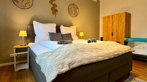 Un lit bien fait, avec des oreillers et une couverture, une armoire en bois et deux éléments de décoration murale.