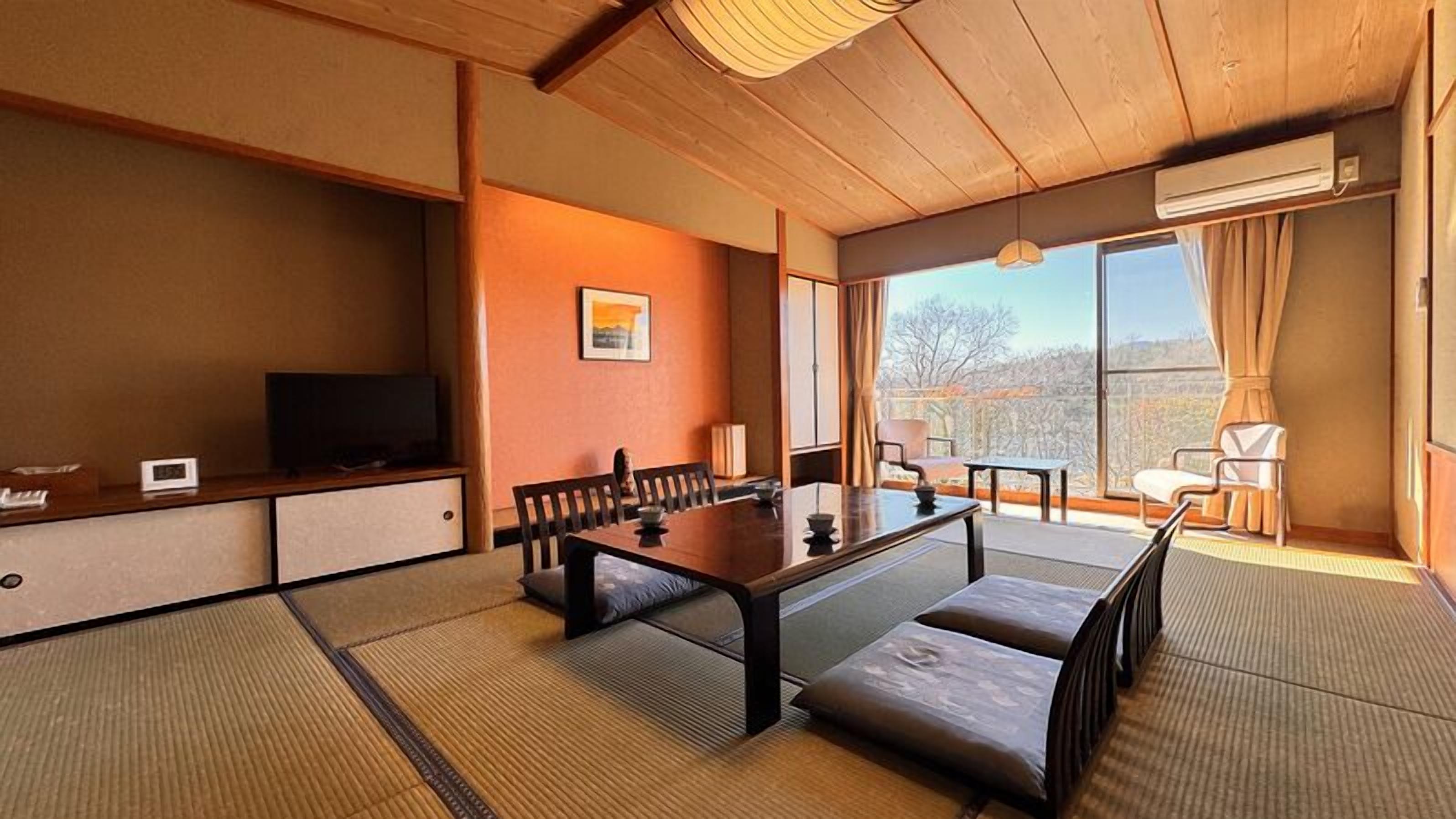 A traditional Japanese-style room with tatami flooring, a low table, and a television on a shelf.