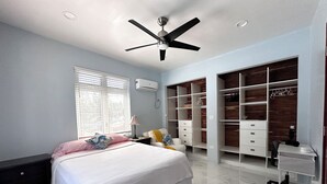 Une chambre à coucher comprenant un lit, un bureau, une chaise, une armoire et un ventilateur de plafond.