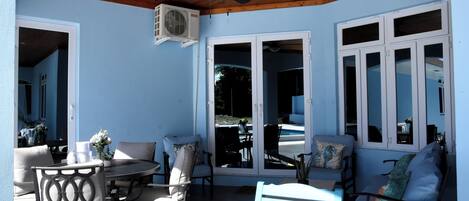 A covered patio area with a ceiling fan, outdoor seating, and a view of the pool.