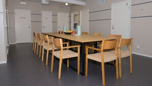 A conference room with a long table and six chairs, equipped with a coffee machine and a fruit bowl. - Britz Hostel (Kristinehamn)