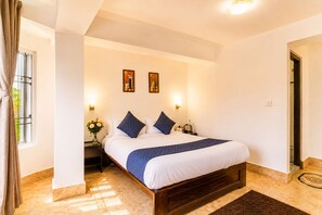 Habitació d'hotel amb un llit, una nit de nit i un ram de flors, i un quadre a la paret.