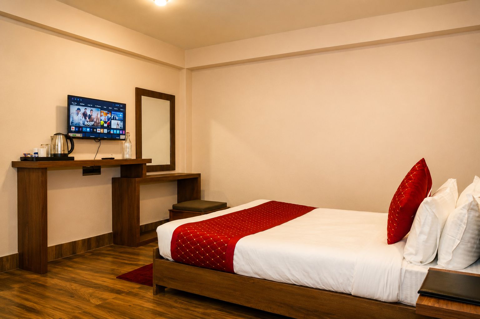 A hotel room with a bed, a desk with a computer, a mirror, and a television.