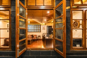A hotel lobby with a wooden reception desk, a sofa, and a dining area.
