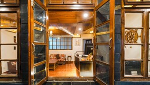 Una zona de recepción con un mostrador de madera, un sofá y un ventanal con vistas al interior.