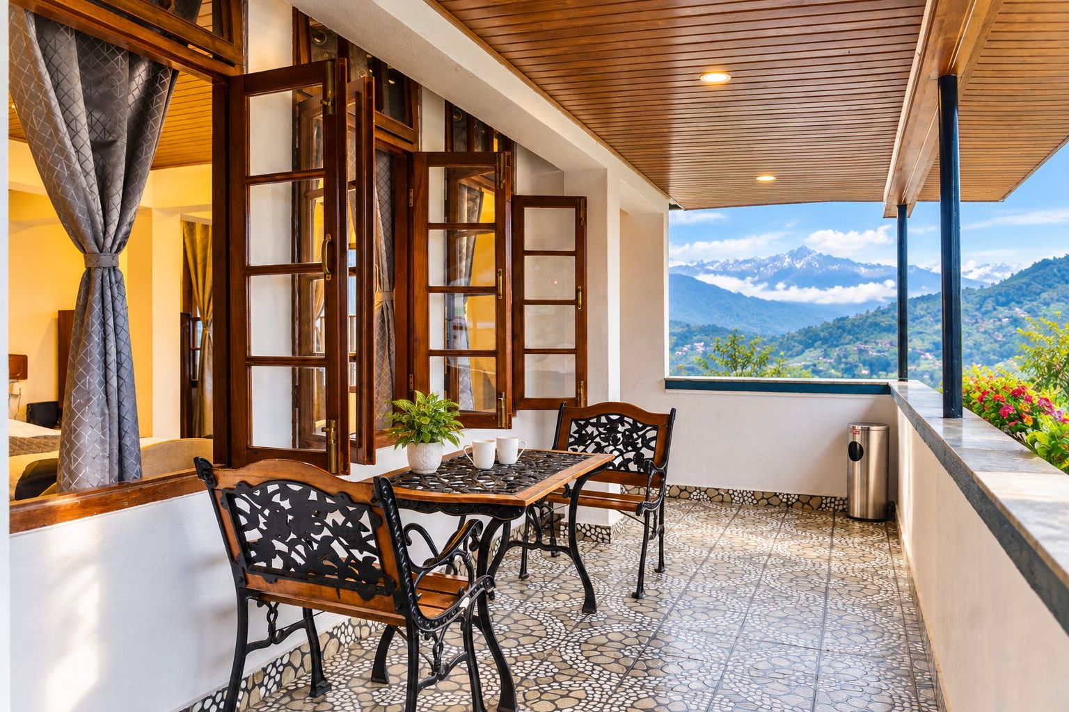 A balcony with a table and chairs, a view of mountains, and a tiled floor.