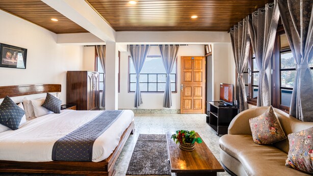 Un dormitorio con una cama grande, techo de madera, un sofá y un televisor.