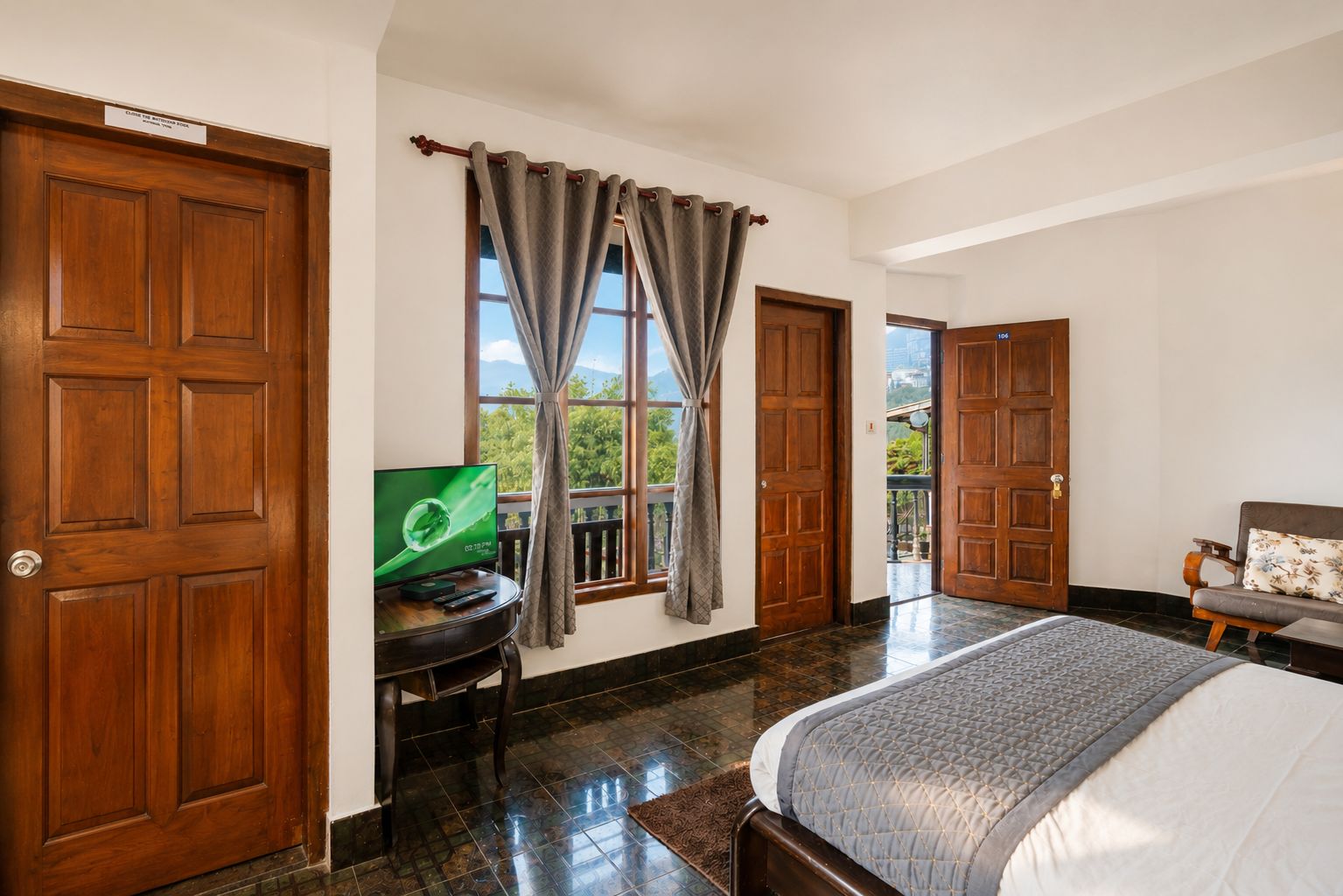 Una camera d'albergo con un letto, una televisione, una scrivania e una finestra con tende.
