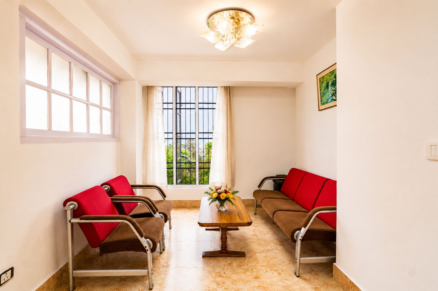 A room with two brown sofas with red cushions, a wooden coffee table, and a chandelier.
