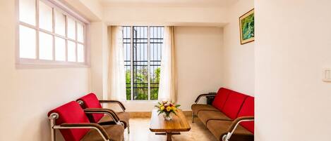 A room with two brown sofas with red cushions, a wooden coffee table, and a chandelier.