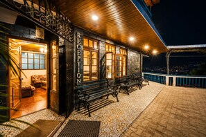 A reception area with a wooden facade, a bench seating area, and a view of the city at night.