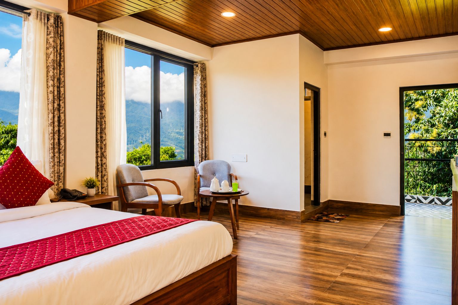 Habitación de hotel con una cama grande, dos sillas, una mesita y vistas al exterior.