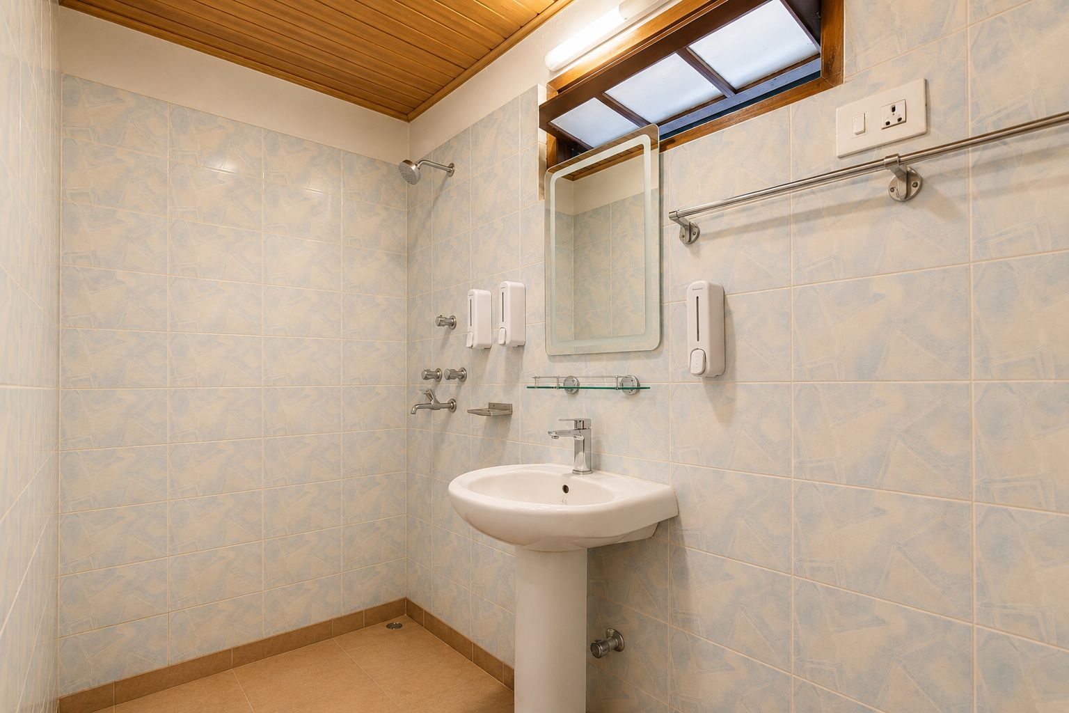 A bathroom with a white sink, a mirror, a towel rack, and a shower.