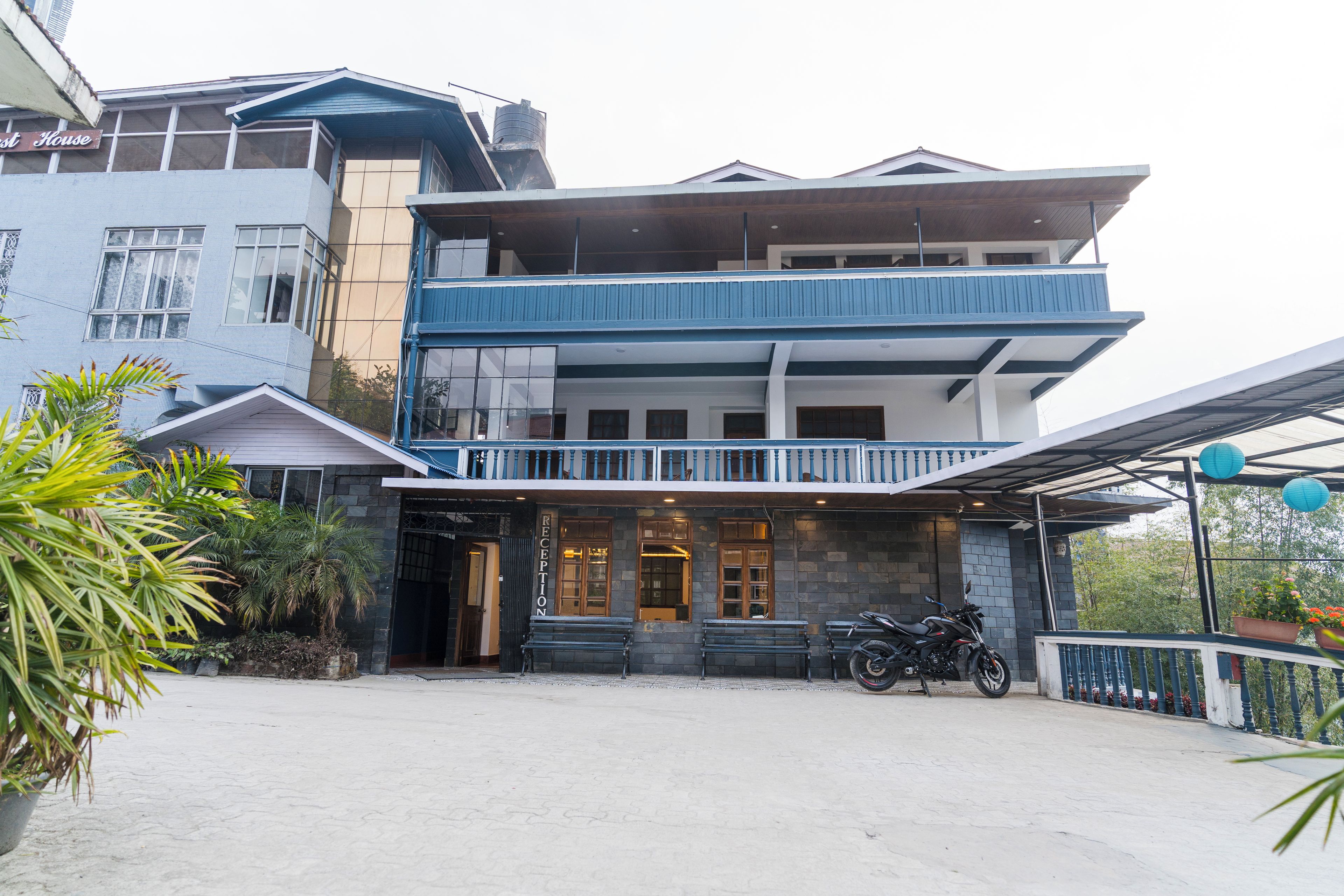A two-story building with a reception area, a balcony, and a motorcycle parked in front.