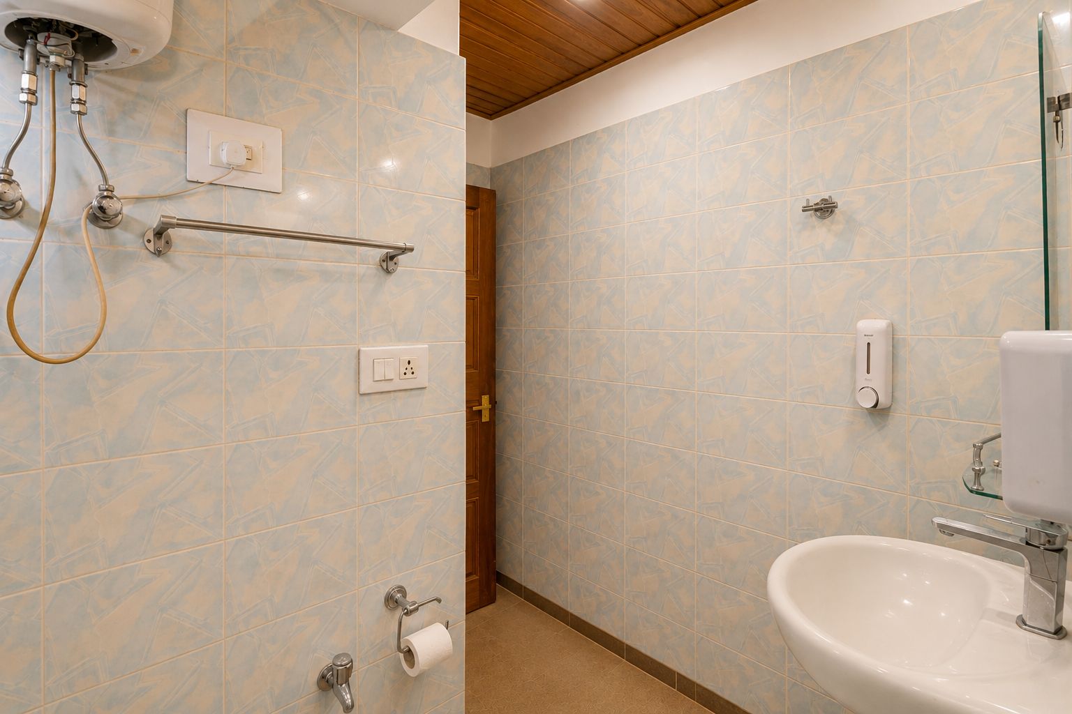 Un baño con ducha, inodoro y lavamanos, con paredes de azulejos y techo de madera.