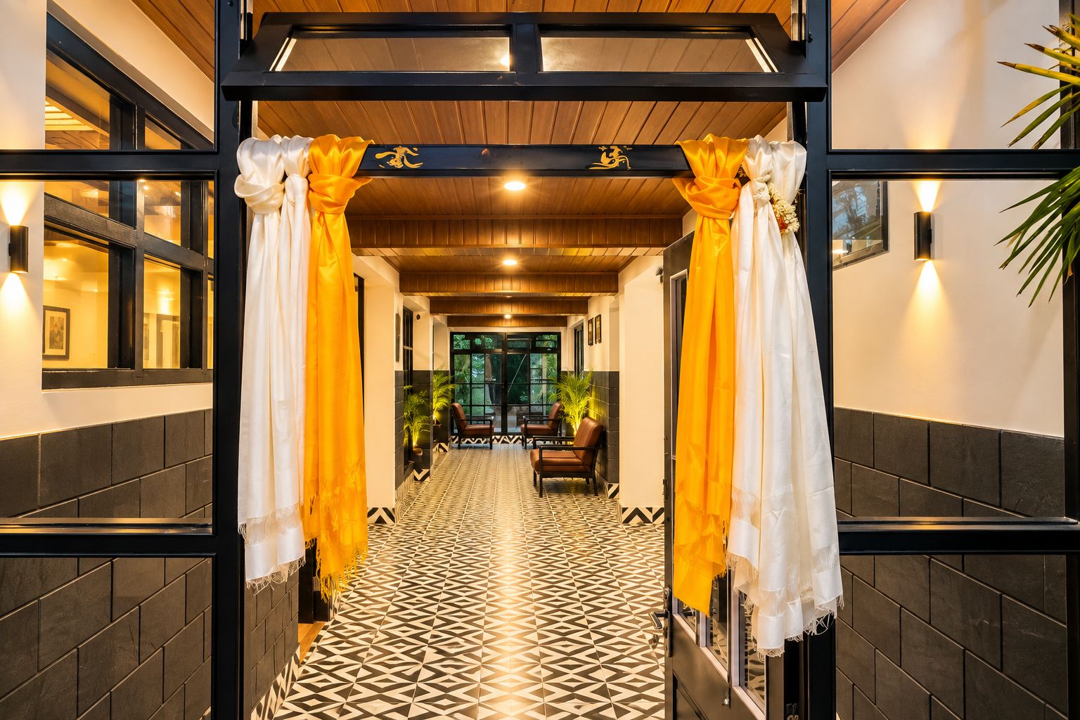 A corridor with a patterned floor, a seating area with chairs, and a decorative archway with curtains.